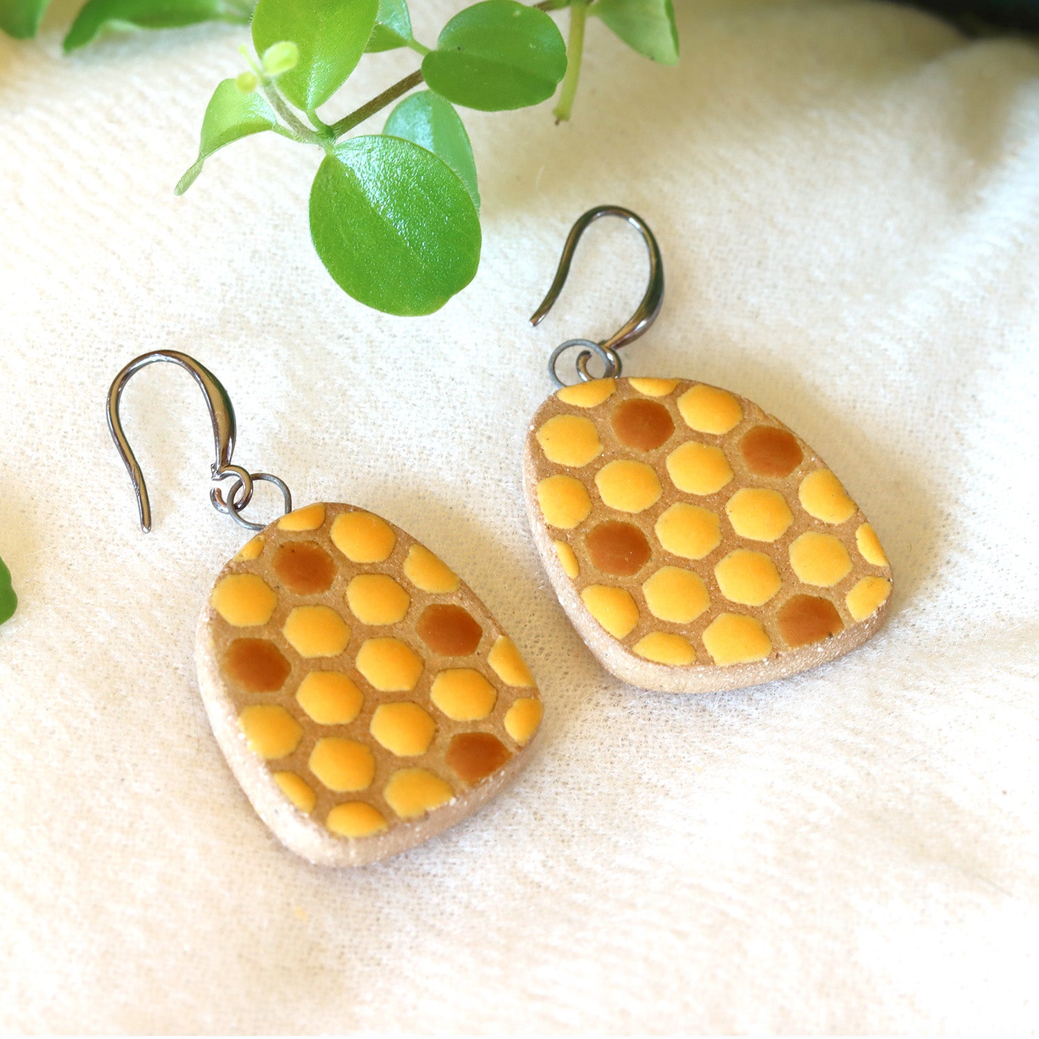 Handmade ceramic earrings with beehive pattern in yellow and brown