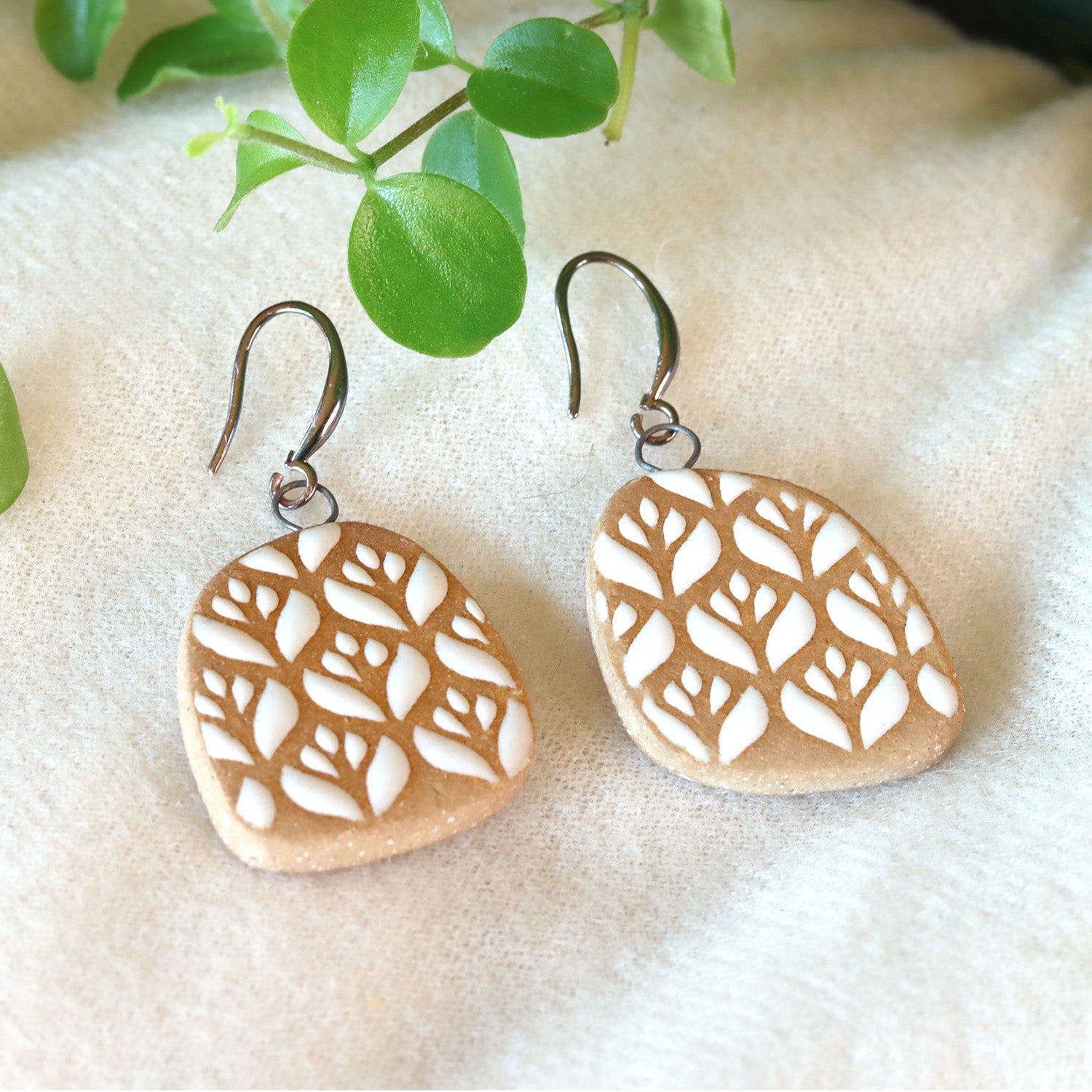Handmade ceramic earrings with white flowered pattern