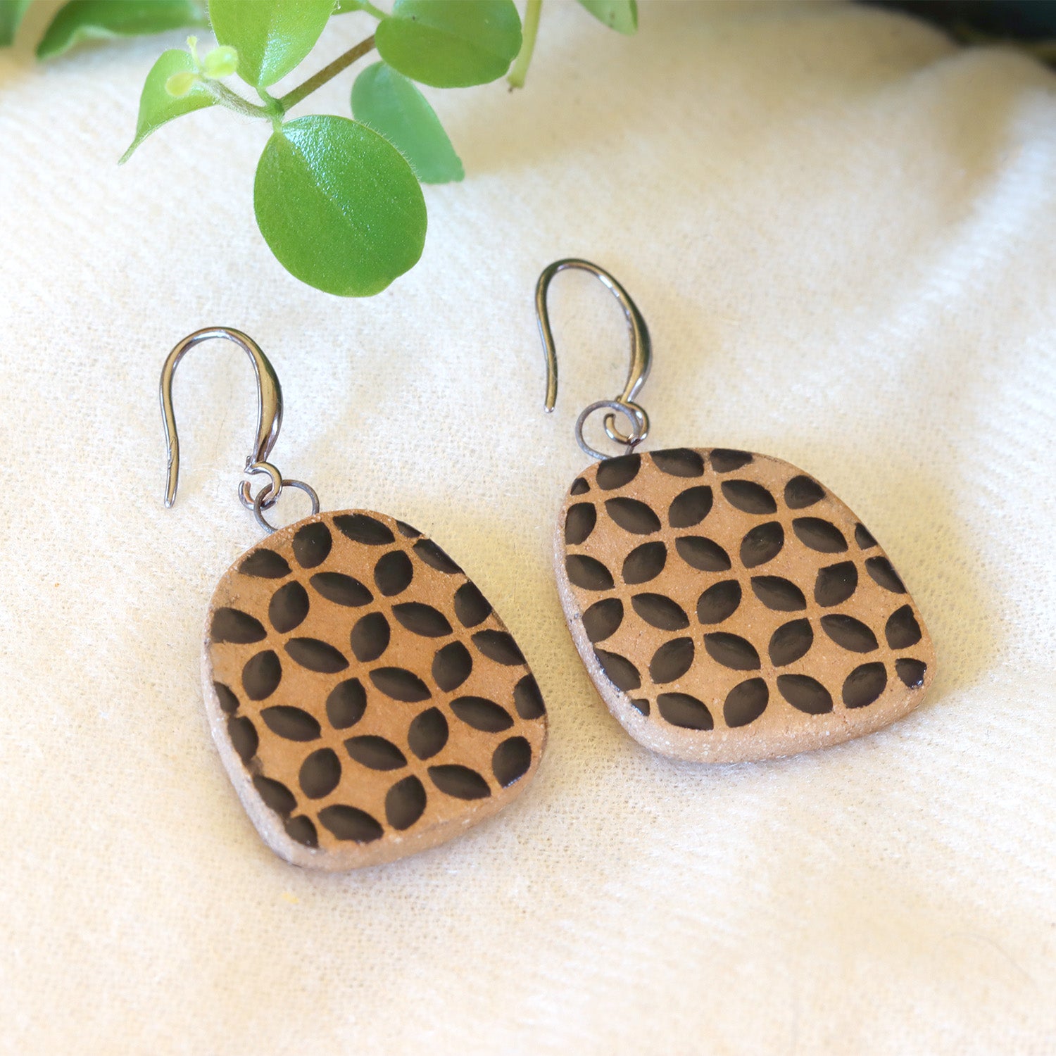 Handmade ceramic earrings with geometrical black pattern