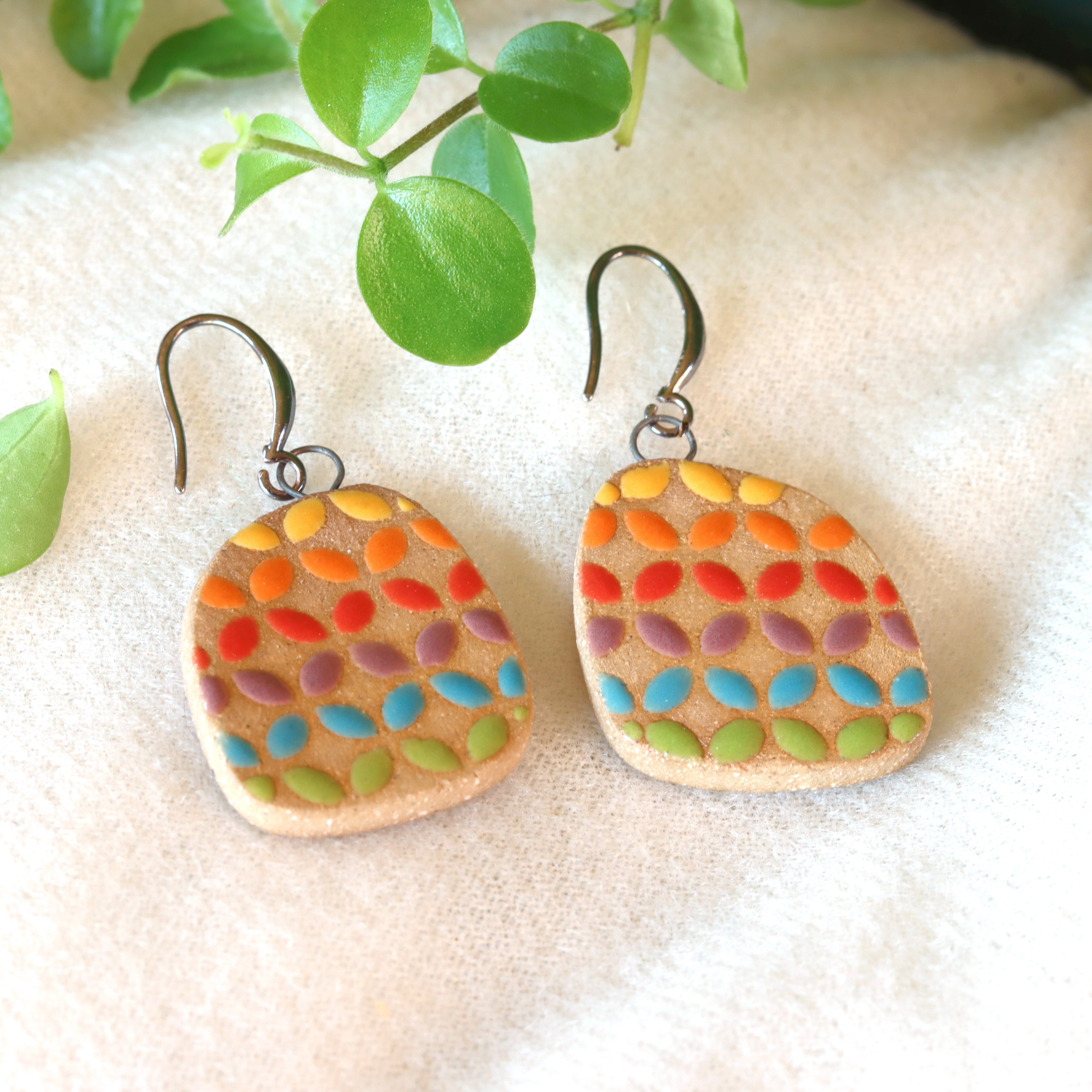 Handmade ceramic earrings with geometric rainbow pattern