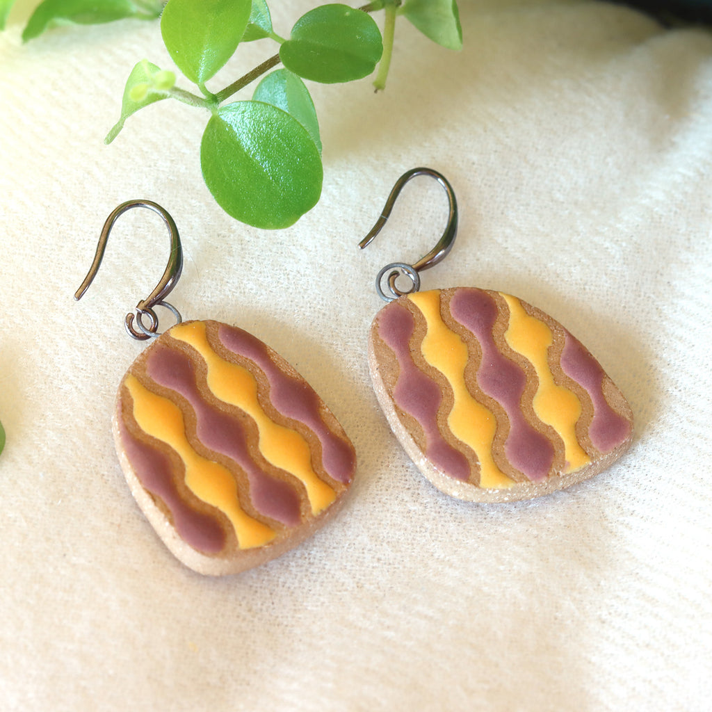 Handmade ceramic earrings with wavy pattern in yellow and purple