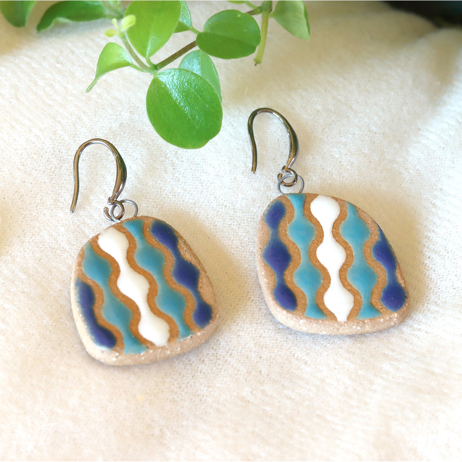 Handmade ceramic earrings with wavy blue and white pattern